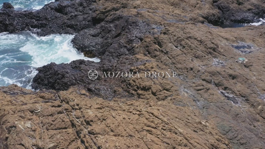 「秋谷の立石」の岩場で荒波の海を眺める女性 ドローン空撮動画素材【神奈川県・横須賀市】
