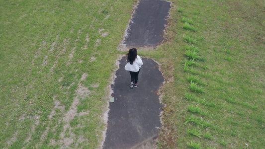 森の中の1本道をランニングする女性 ドローン空撮動画素材