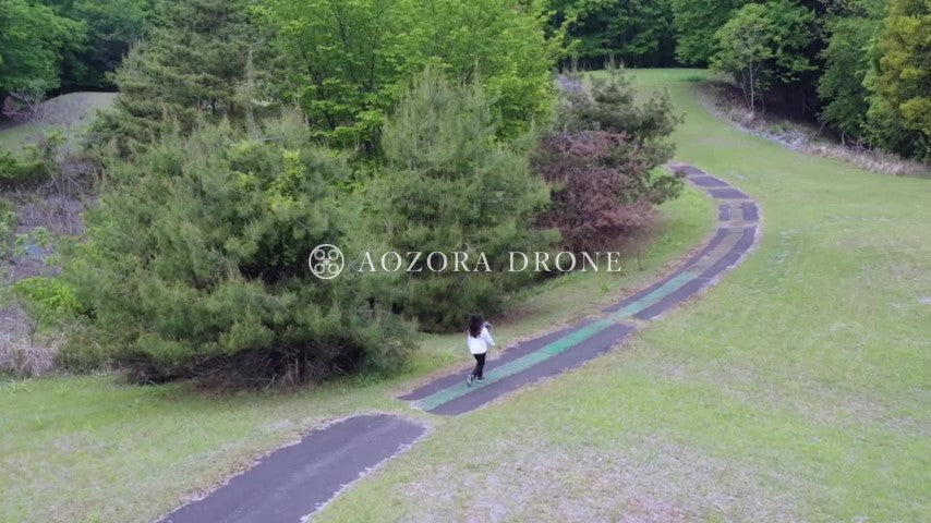 A woman walking lightly while piloting a drone on a mountain road Drone aerial video footage Japan drone video