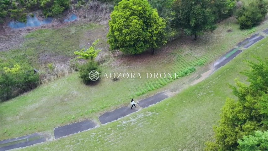 A woman walking slowly on a single road in a forest rich in nature Drone aerial video footage